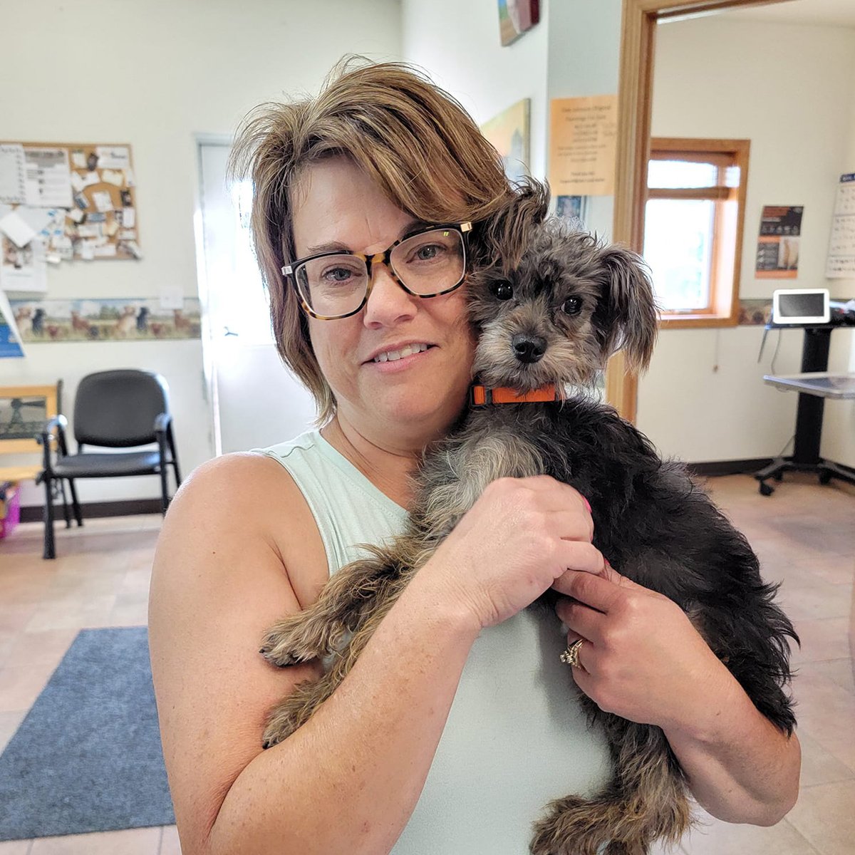 a woman embraces a small dog in a comfortable room