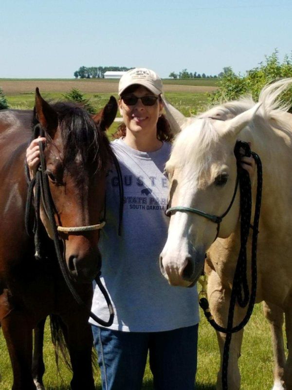 a woman standing next to two horses in a field
